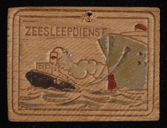 houten winterhulpspeld met daarop ingestempeld en ingekleurd tafereeltje van de "zeesleepdienst",…