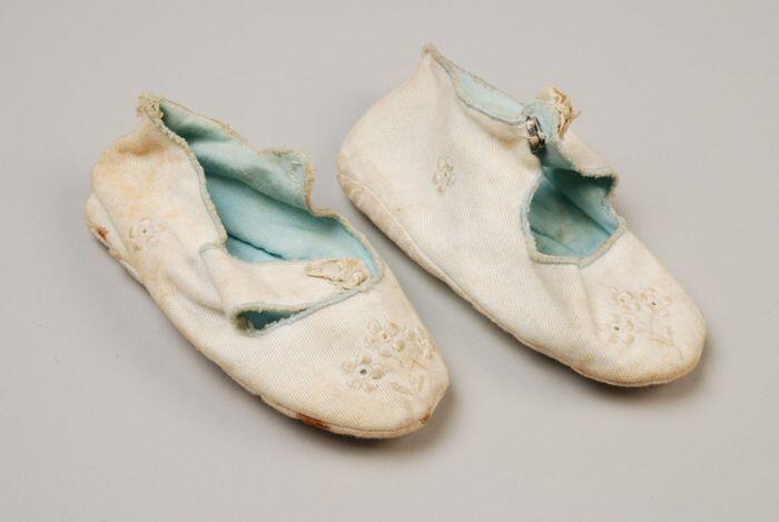 Babyschoenen van wit katoen met lichtblauwe voering en ajour geborduurde bloemetjes en strikje op…