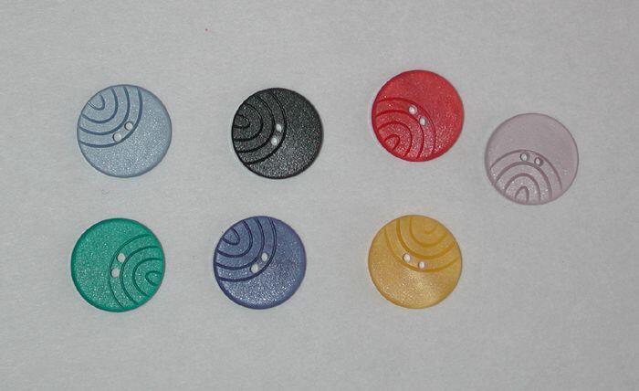 Zeven ronde knopen in verschillende kleuren, met vier ingekerfde bogen