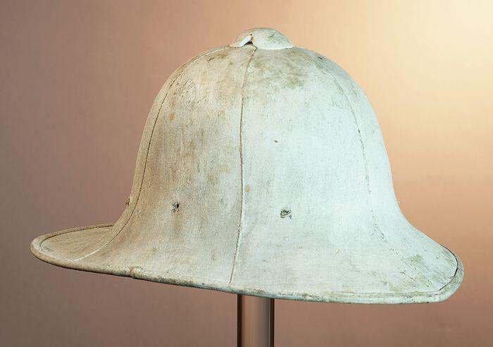 Tropenhelm van wit geverfd textiel, rand voor aflopend in een punt, achter in brede rechte rand,…