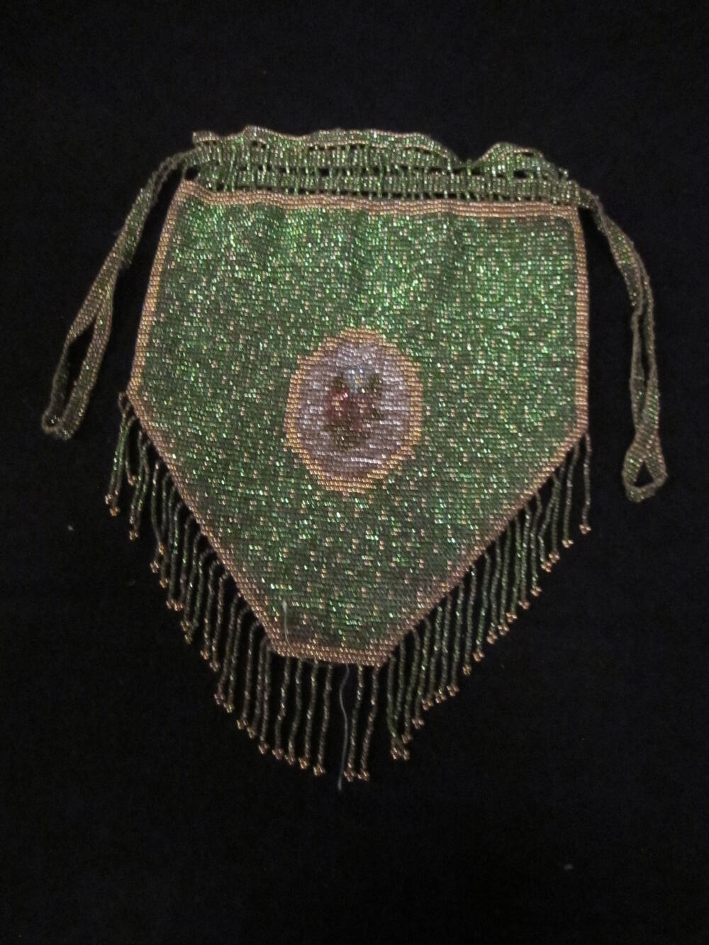 Avondtas van kralenwerk van groen kralenfond met stippen van goudkleurige kralen. Buidelvormig…