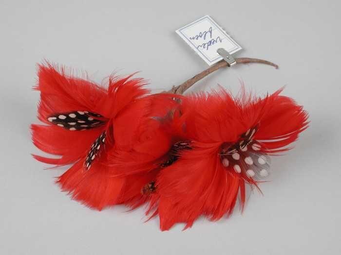 Corsage, drie bloemen van rode veren met hart van twee zwart-wit gespikkelde veren, op kort bruin…