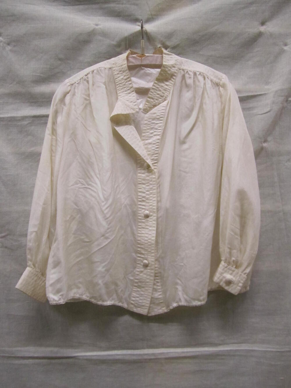 Blouse van witte zijde met ronde halslijn, schouderstukken, voorpanden uitlopend in een punt