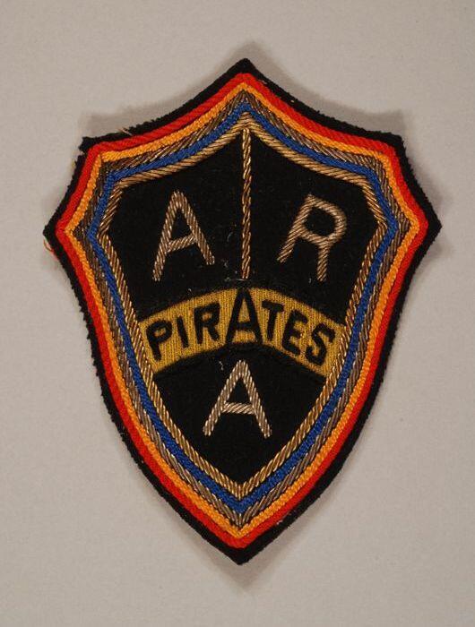 Stoffen badge "ARA" "Pirates", schildvormig omlijst met kleurige banden zwarte ondergrond met…