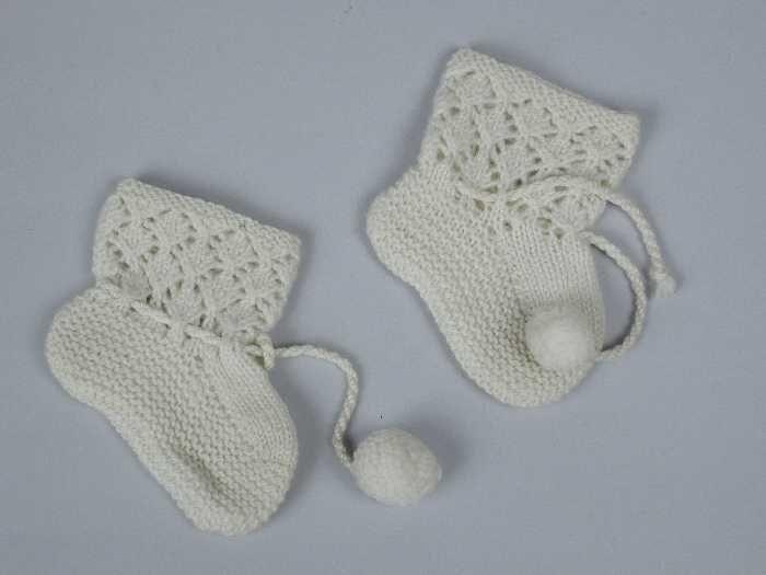 Paar korte babysokken gebreid van crèmekleurige dunne wol in tricotsteken en ajour, koordje met…