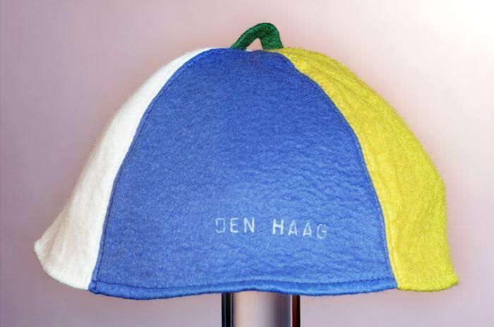 Rond vilten vakantiemuts (?) van vier delen rood, wit, blauw en oranje met groen lusje middenop, in…