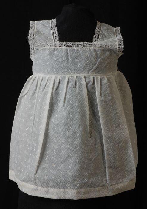 Babyjurk, mouwloos schortmodel van transparant wit seersucker-achtig nylonmet wit kant en witte…