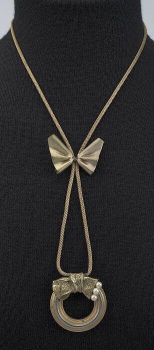 Goudkleurige metalen ketting, met schuifstrik en ronde metalen hanger met strik en drie parels