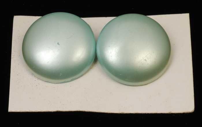 Paar oorbellen, clip met ronde mintgroene plastic knop met paarlemoerglans, op wit karton, kapper…