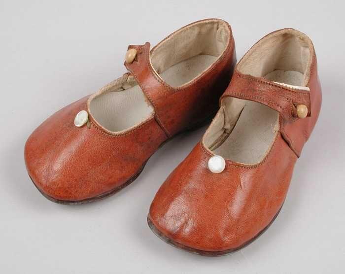 Bruine leren kinderschoenen met wreefbandje met knoopsluiting, parelmoeren sierknoopje op de…