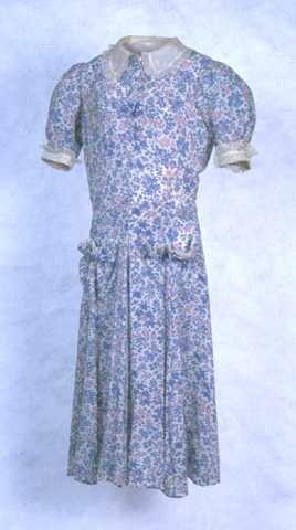 Meisjesjurk van wit rayon bedrukt met roze, blauwe en lila bloemetjes, wit voile kraag, manchetten…
