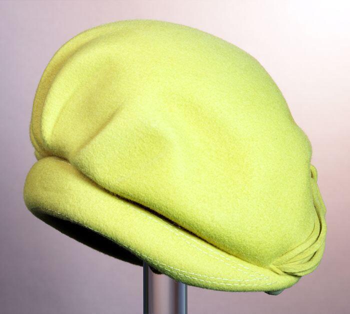 Gele vilten baret, toque, met sierknoop van viltrepen, sierplooien