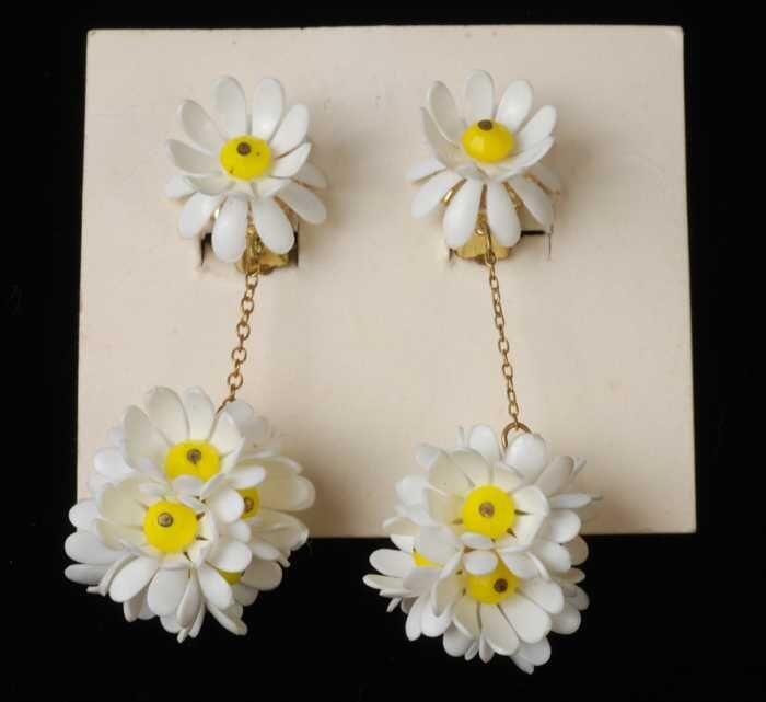 Paar oorbellen, clips met een bol van witte plastic bloemetjes aan een kettingje, op wit karton,…
