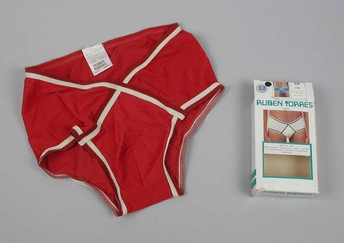 Heupslip (1) van glanzend wijnrood tricot met crèmekleurige elastiek schuin over de voorzijde met…