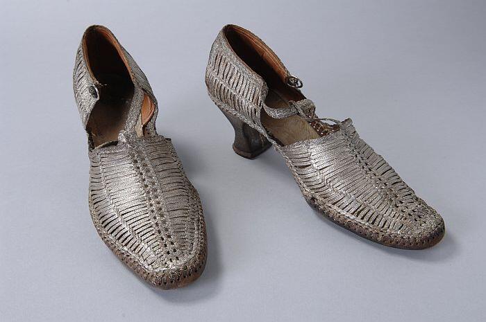 Hakschoenen van gevlochten zilverbrokaatband met T-bandje op de wreef met gespsluiting