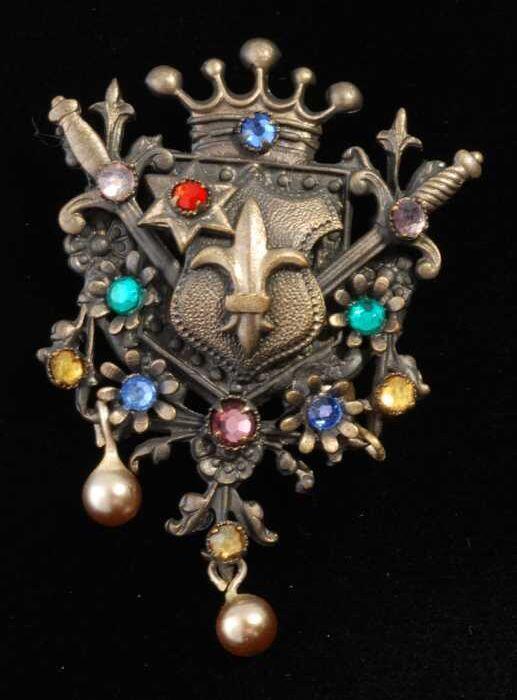 Broche, gekroond wapenschild van donker metaal met gekleurde kunstdiamantjes, kapper Van Vliet