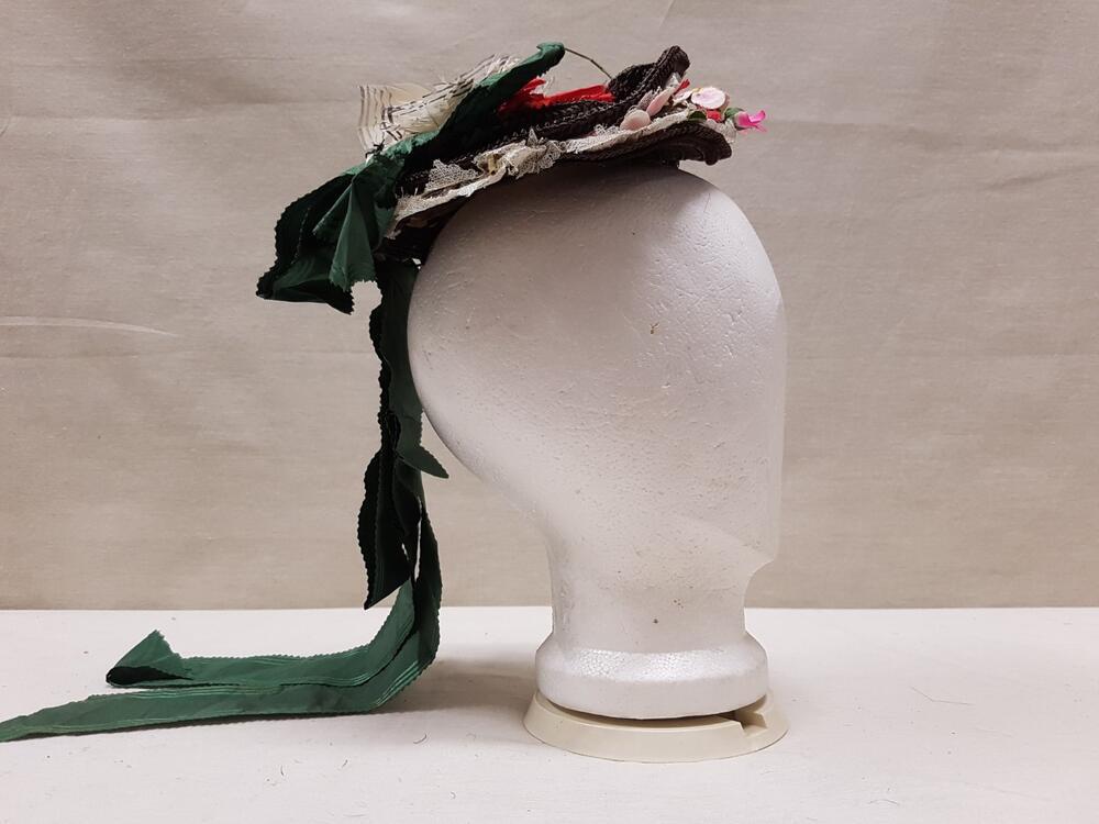 Hoedje klein rond model, bruin stro, met garnering van witte veren, kant en kunstbloemen en groene…