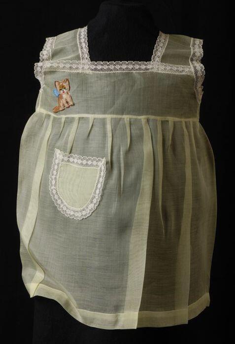 Babyjurk, mouwloos schortmodel van transparant geel nylonmet wit kant en geborduurd poesje, …