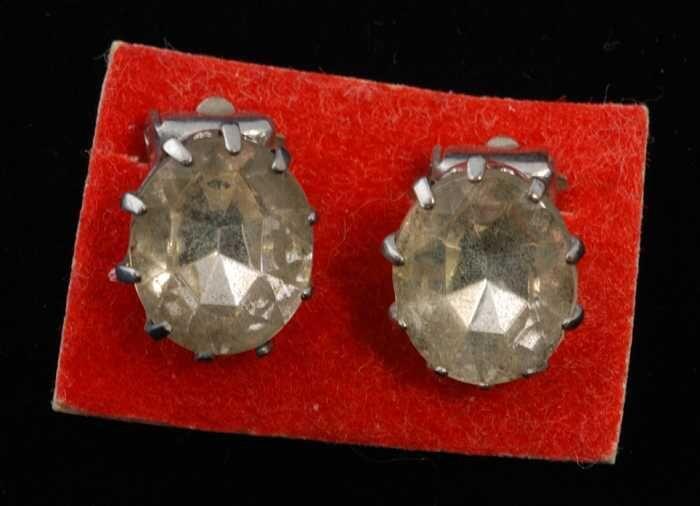 Eén paar oorbellen, clip met ovale kunstdiamant op hoge zilverkleurige vattin, op rood…