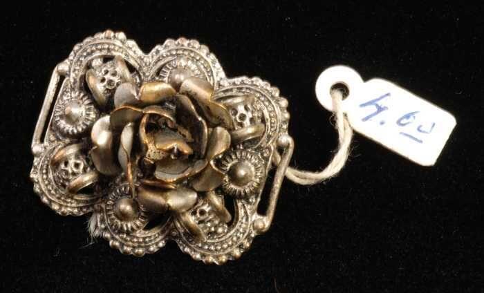 Broche, bloemvorm op een filigrein-achtige ondergrond van zilverkleurig metaal, kapper Van Vliet