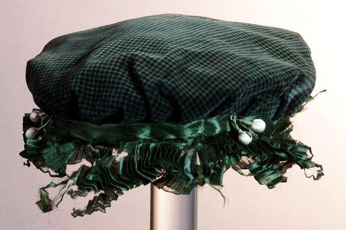 Ovaal meisjeshoedje van groen gestreept fluweel, rand met groen lint en witte bolletjes, binnen wit…