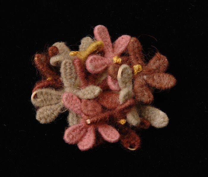 Corsage bestaande uit bloemetjes, hartjes van gele zijde bloemetjes in bruin, roze en beige