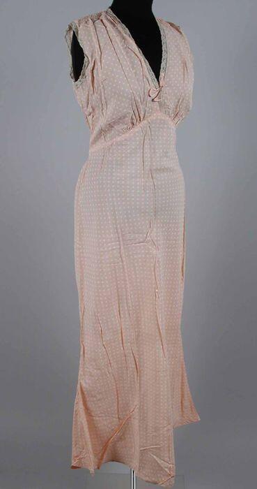 Lange mouwloze nachtjapon van roze viscose met witte noppen, diepe V-hals, kant langs hals en…