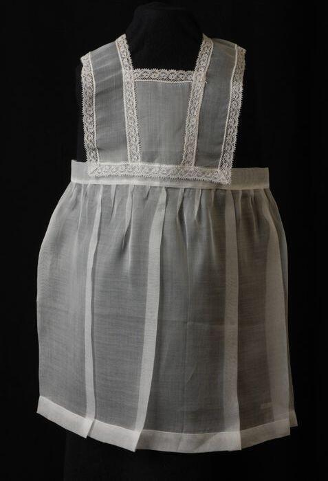 Babyjurk, mouwloos schortmodel van transparant wit nylonmet witte kantjes, 'Femifra' model 'Netty'