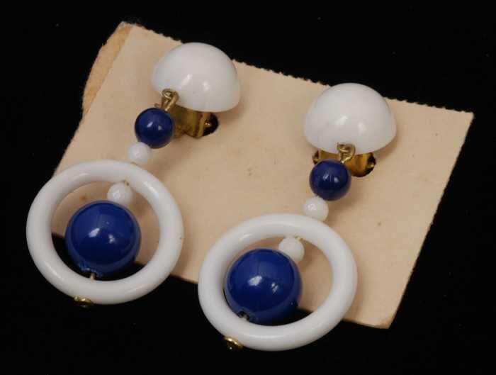 Paar oorbellen, clip met hanger van wit plastic, witte ring met blauwe en witte kralen, op wit…
