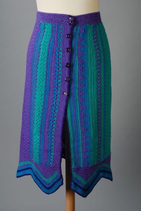 Rok van tweedelig ensemble, gehaakt in verticale, groene, paarse en turquoise banen, afgezet met…