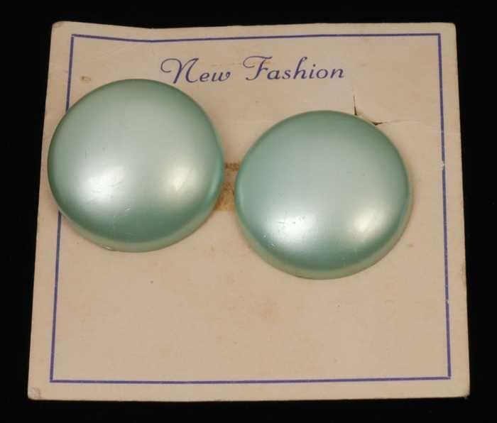 Twee paar oorbellen, clip met ronde mintgroene plastic knop met paarlemoerglans, op karton, kapper…