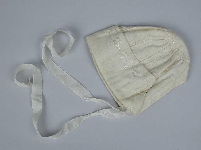 Babymuts van crèmekleurig flanel met zijde voering en strikbanden, oprijgjes en glanzend…