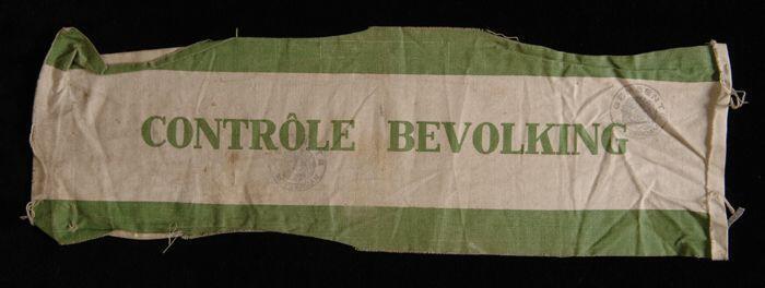 Wit katoenen mouwband, opdruk in groen "CONTRÔLE BEVOLKING" tussen twee groene banen, stadskleuren…