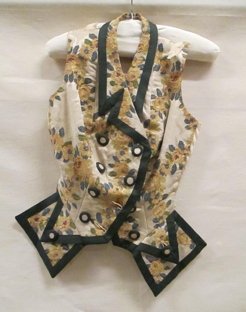 Vest (vrouw), beige ribszijde met ingeweven bloemen in geel/bruin, afgebiesd met groen