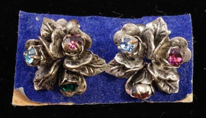 Paar oorbellen, clip met drie zilverkleurige metalen bloemetjes met gekleurde kunstdiamantjes, op…