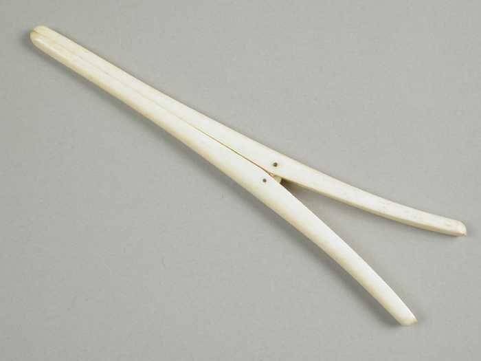 Handschoenrekker van been, twee spits toelopende poten met metalen veer