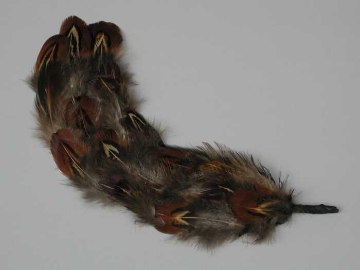 Veren hoedendecoratie of corsage, zwarte veer beplakt met eendeveertjes in grijs, bruin, geel en…