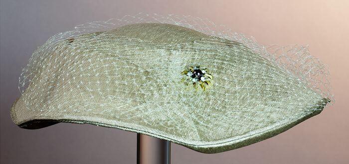 Dameshoed van beige stro met ingeperste belijning, overtrokken met beige voile, garnering met…