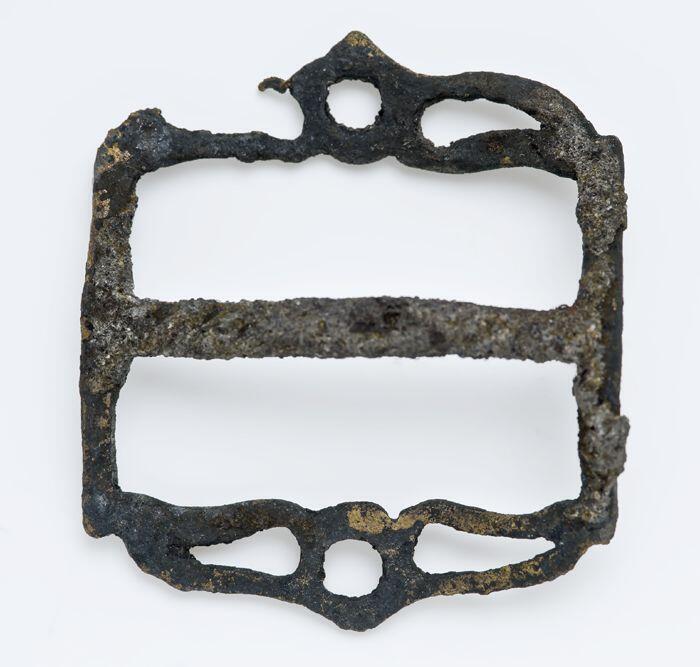 Gordelaccessoire in de vorm van een gesp met een uitgebogen middenstijl, waaronder een ophangoog