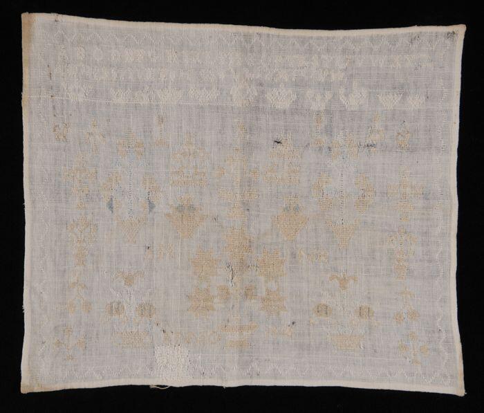 Merklap of letterlap van wit katoengeborduurd in kruissteek in wit, beige en bleu zijde gemerkt "AM…