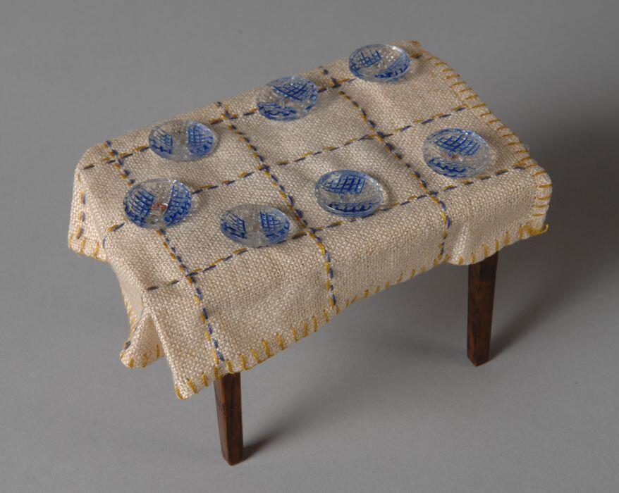 Zeven glazen knopen in poppenhuis gebruikt als bordjes, onderzijdegroefjes met blauwe decoratie