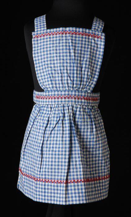 Kinderschort van blauw-wit geruit katoen met borduursel in rood, oefening