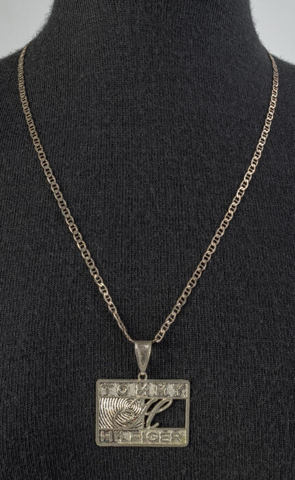 Rechthoekige zilveren hanger "Tommy Hilfiger" aan zilveren ketting van platte schakels