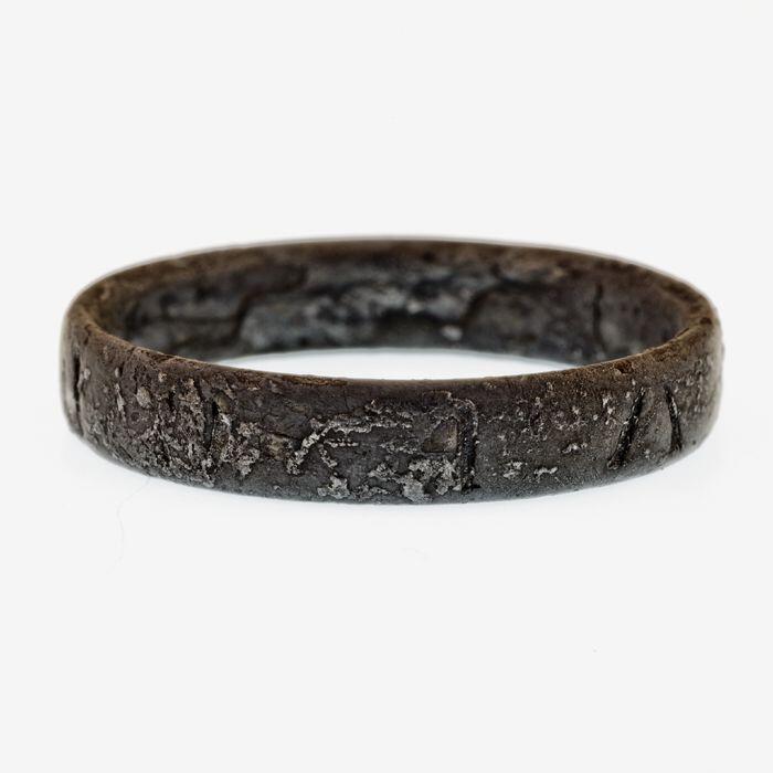 zilveren ring waarop enkele letters en figuren