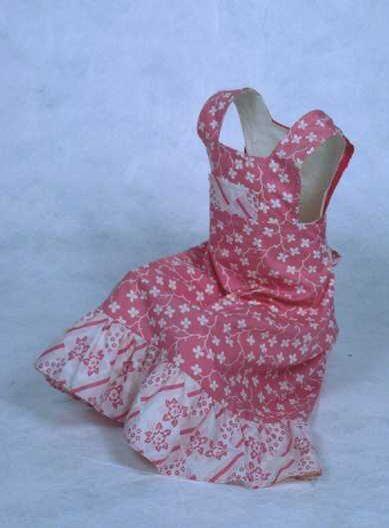 Roze met witte gebloemde kinderovergooier met aangerimpelde onderrand en linten op de rug te…