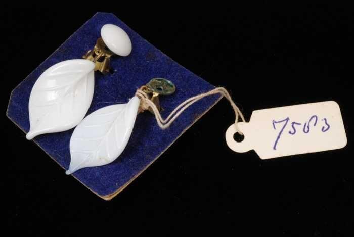 Paar oorbellen, clip met bladvorm van wit glas op blauw fluweelkarton, kapper Van Vliet