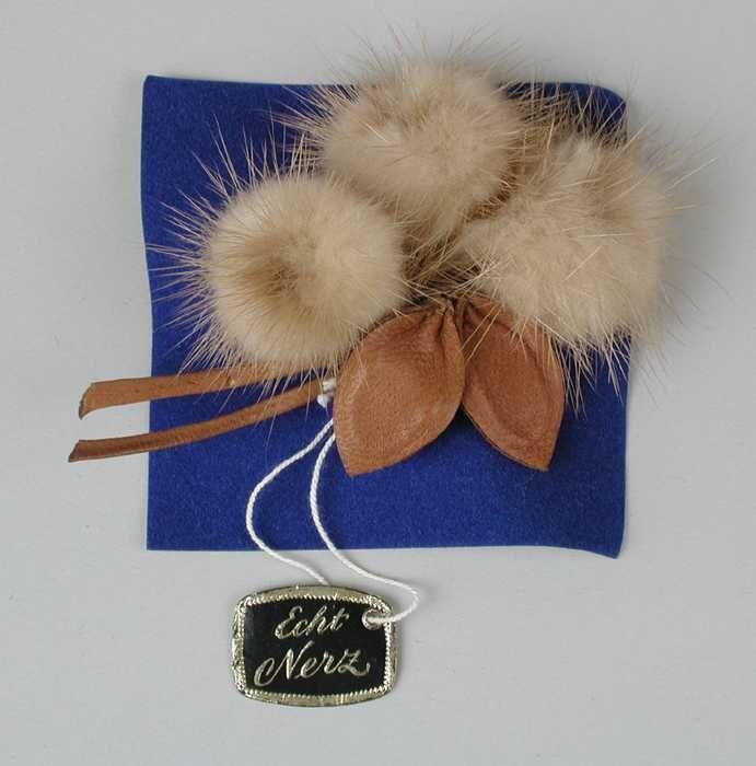 Corsage van lichtbruin nertsbont met bruin leer, leren takje met blaadjes, bolletjes van bont als…