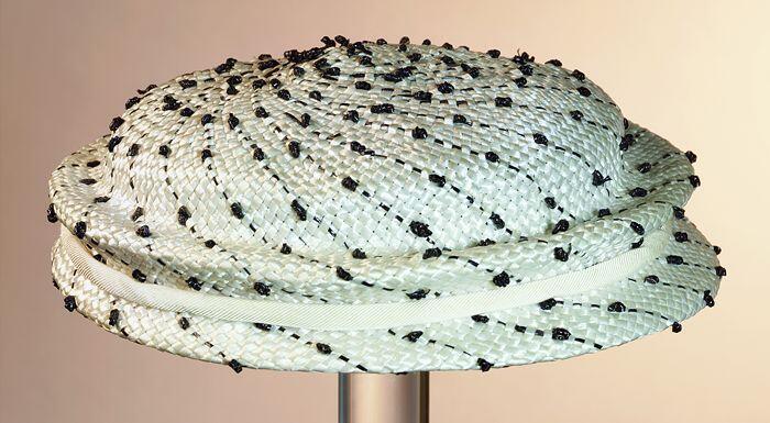 Dameshoed, rond laag model zonder hoedrand, wit raffia(?) met zwarte spiraalvormige decoratie…