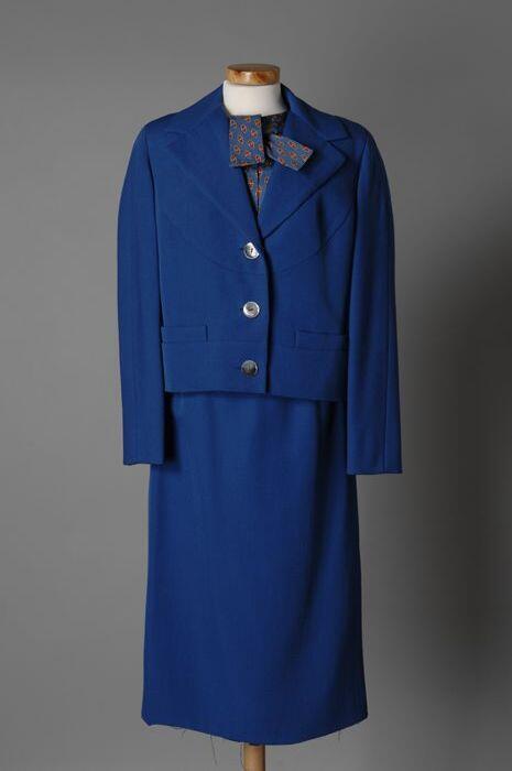 Blauw mantelpak met blauwe blouse, voorzien van rood motief