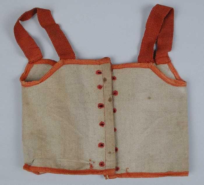 Poppenkorset of keurslijf van beige visgraatkeper met rode biezen met brede rode elastieken…
